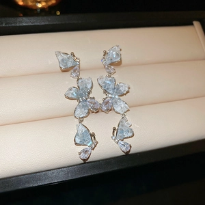 Détail de boucles d'oreilles argentées avec trois papillons en cristal bleu sur plateau