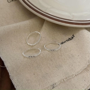Three-piece set of minimalist 925 sterling silver hollow heart rings on fabric background