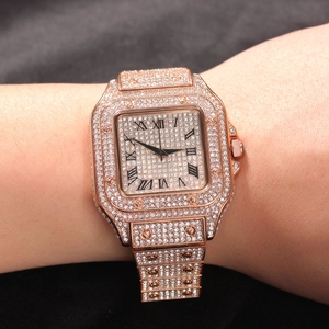Close-up of rose gold iced-out square watch with Roman numerals on a male wrist