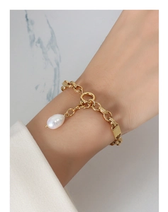 Close-up of 18k gold-plated thick chain bracelet with baroque pearl and metal tag