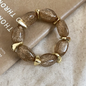 Detailed macro view of acrylic amber beads with gold glitter and geometric spacers