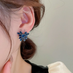 Close-up of a silver stud earring featuring deep blue marquise-cut crystal butterfly wings