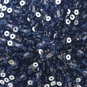 Macro shot of navy denim texture with silver sequins and distressed fringe details