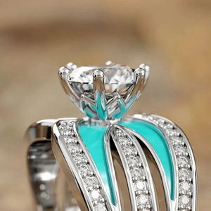 Macro shot of silver ring with crown-set round gem and vibrant green enamel detailing