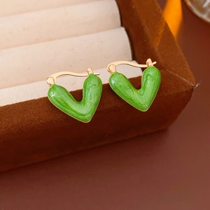 Close-up of green enamel V-shaped heart earrings on a brown velvet jewelry display stand
