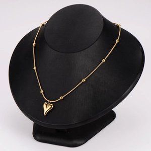 Elegant gold heart pendant necklace with beads displayed on a black mannequin