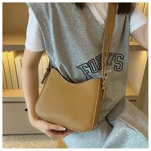 Brown leather crescent crossbody bag with adjustable strap worn by a model in casual style