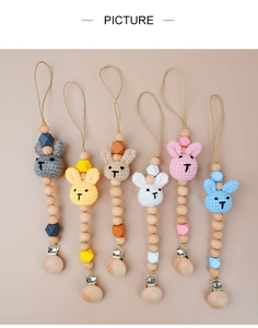 Flat lay of six colorful baby pacifier clips with crochet bunnies and beech wood beads