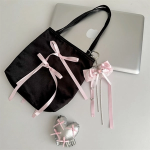 Detail of black velvet tote bag with pink satin bows and a silver heart-shaped charm