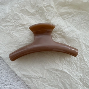 Detail view of a brown amber resin hair claw clip with a glossy finish on white paper