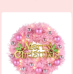 Detailed close-up of pink Christmas wreath with silver balls and glowing LED lights
