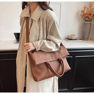 Detailaufnahme einer braunen Leder-Tragetasche mit Litschi-Muster und Trageriemen