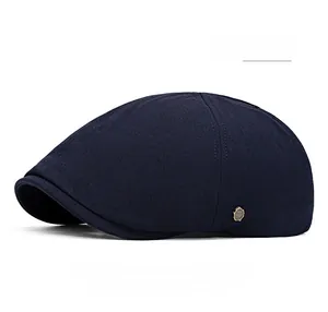 Détail d'une casquette plate bleu marine avec bouton logo en métal bronzé sur le côté