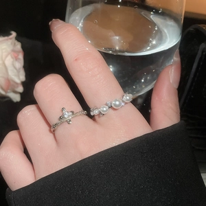 Detail of elegant pearl row ring and zircon cross ring worn with minimalist style