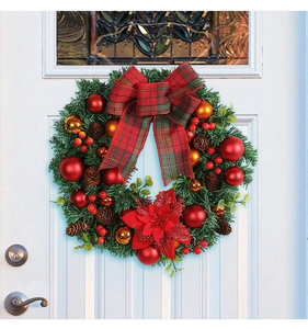 Christmas wreath with red plaid bow and ornaments hanging on a white front door