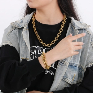 Close-up of a man wearing a thick gold-tone chain link necklace and matching bracelet set