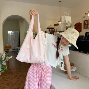 Close-up of pink organza tote bag with white floral embroidery and delicate lace edges