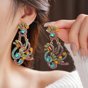 Detailed close-up of vintage peacock earrings with colorful crystals on a bronze setting