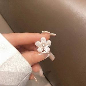 Floral hair clip with pearlescent five-petal flower and central zircon held in hand