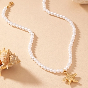 Elegant pearl necklace with golden starfish pendant on sand background for beach fashion
