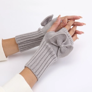 Detailed texture of grey knitted fingerless gloves with a large sweet bow decoration