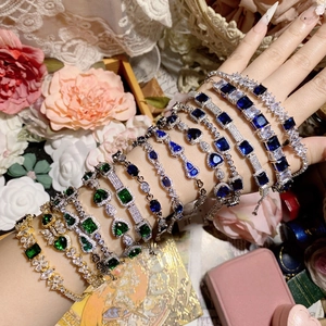 Detail of vintage-style gold bracelets with vibrant emerald and sapphire gemstones