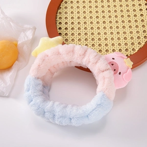 Détail d'un bandeau en peluche rose et bleu avec cochon de dessin animé et étoile