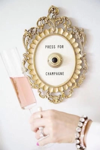 Detail of vintage Press For Champagne wall plaque held with a luxury glass of pink wine