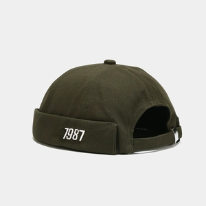 Dettaglio del cappello Miki verde scuro con ricamo 1987 e fibbia metallica regolabile