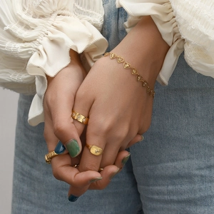 Golden heart charm bracelet and vintage starburst rings set on model for daily styling