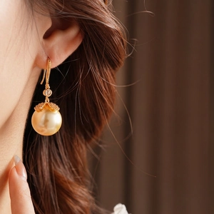 Élégantes boucles d'oreilles perles fleurs dorées avec zircons sur fond brun doux