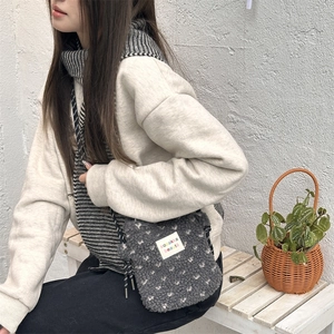 Detail of dark grey plush crossbody bag featuring white heart patterns and rope strap