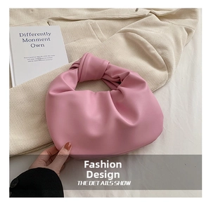Detail of soft pink gathered cloud bag with stylish knotted handle on velvet fabric