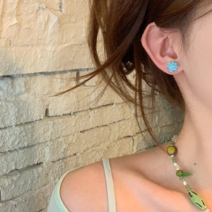 Close-up of model wearing blue flower earrings and a colorful beaded necklace