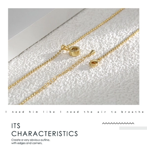 Macro detail of gold bead chain necklace featuring lobster clasp and extension link