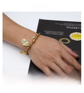 Detailopname van een vergulde Hamsa Hand armband met blauwe emaille oogbedeltjes