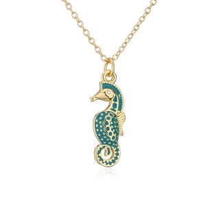 Macro shot of 18K gold seahorse necklace with teal enamel and diamond detail