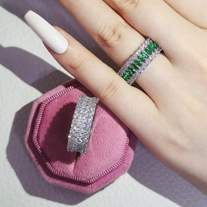 Detailed view of multi-row zircon rings with emerald green stone on pink velvet box