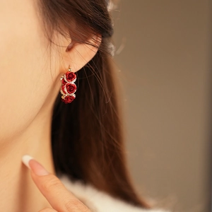Detail of vintage gold plated floral earrings featuring three red roses and rhinestones
