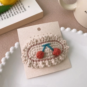 Détail d'une barrette à cheveux en tricot avec cerises sur carte de présentation