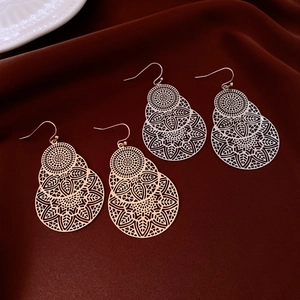 Macro detail of hollow leaf flower earrings in rose gold and silver finishes