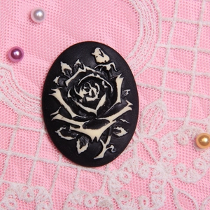 Macro view of black resin oval cameo brooch with white rose on pink lace background