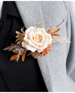 Détail d'une boutonnière rose champagne avec feuilles dorées et perles sur un manteau