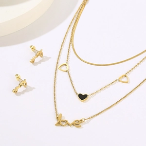 Close-up of gold layered necklace set with black shell hearts and love lettering detail