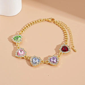 Détail d'un bracelet doré de luxe orné de cinq cœurs en cristal colorés et étincelants