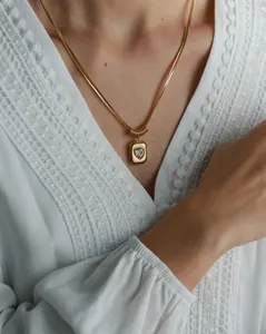 Detail view of a gold double-layer snake chain necklace with a heart-shaped stone pendant