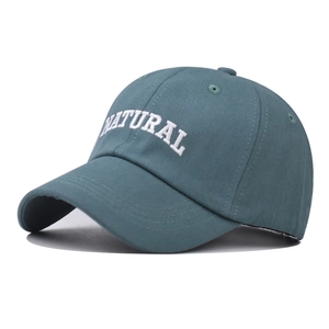 Detailed view of white NATURAL letter embroidery on dark green cotton baseball cap