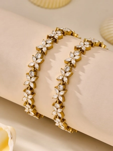 Detailed macro view of two gold flower bracelets with 5A zircon stones on a beige roll