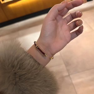 Bracciale rigido aperto in pelle intrecciata rossa con dettagli in metallo dorato
