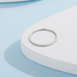 Close-up of minimalist silver stainless steel thin ring on white geometric display stand